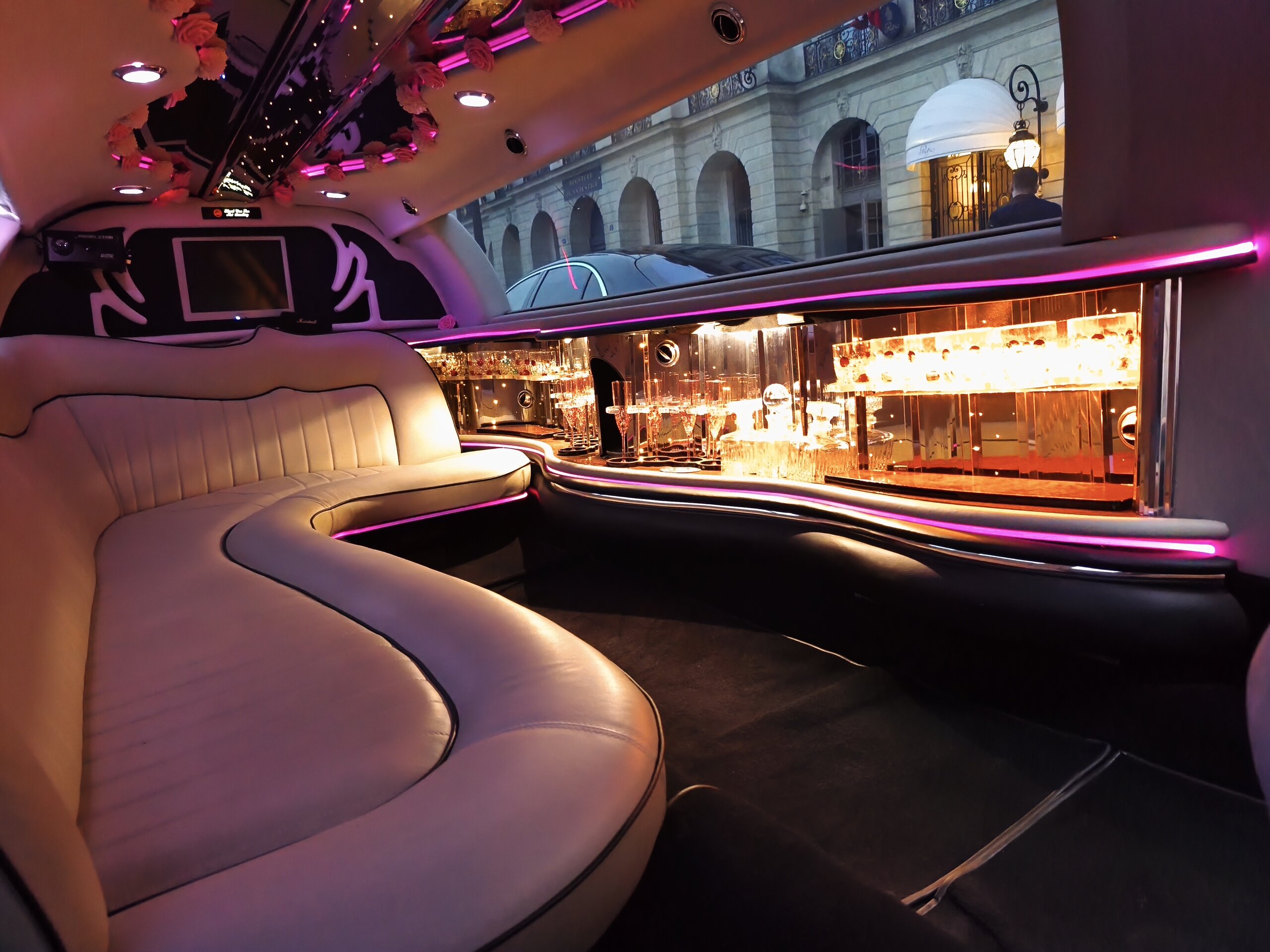 Intérieur de la limousine Lincoln rose : banquettes cuir, bar éclairé et lumières LED